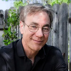 A man with glasses wearing a black polo