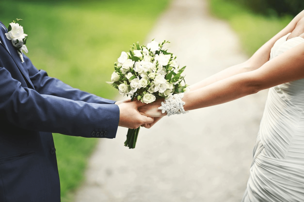 bride and groom hands in hand with a bouquet