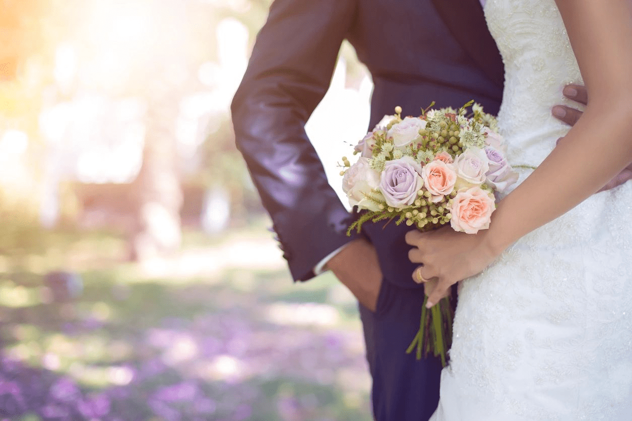 a bouquet in brides hand and grooms hand in pocket