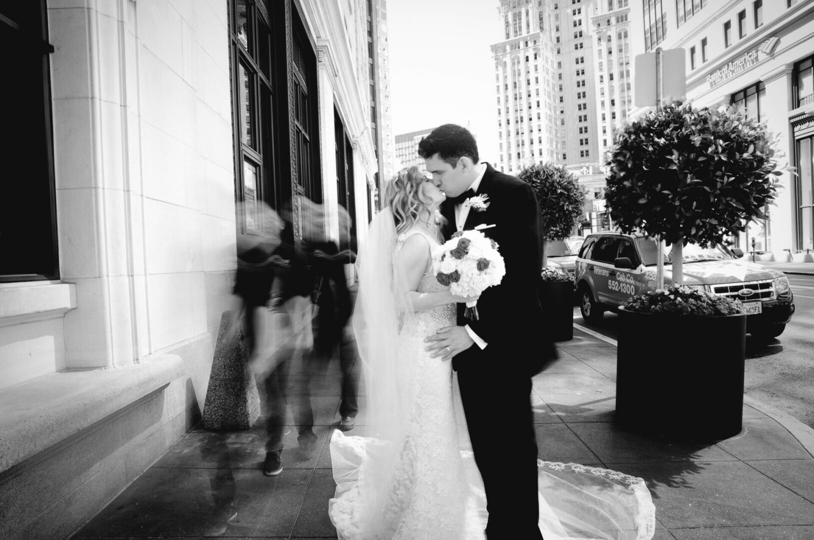 Black and white image of a couple kissing on street