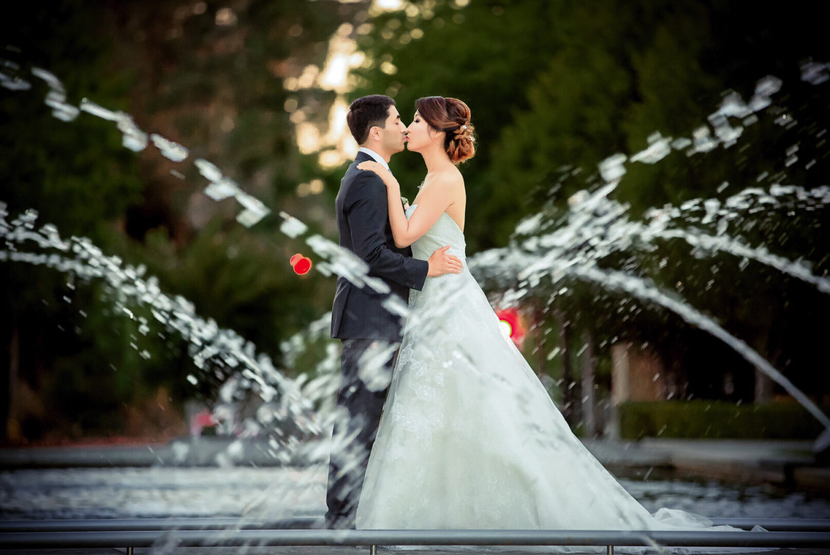 A couple kissing on the street between a fountain