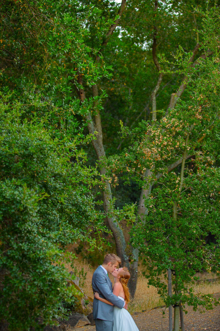 A newly married couple kissing inside a jungle