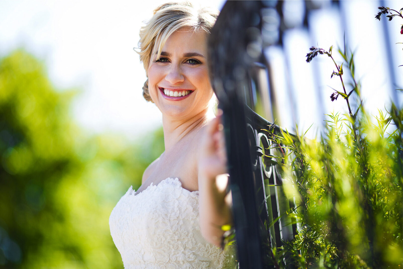 A new bride along wearing a white color dress near fence